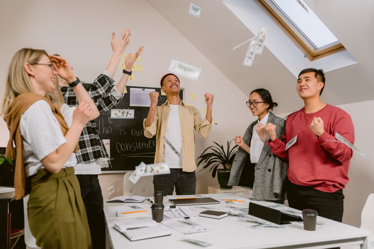 Diverse team excitedly celebrating success in a modern office setting.